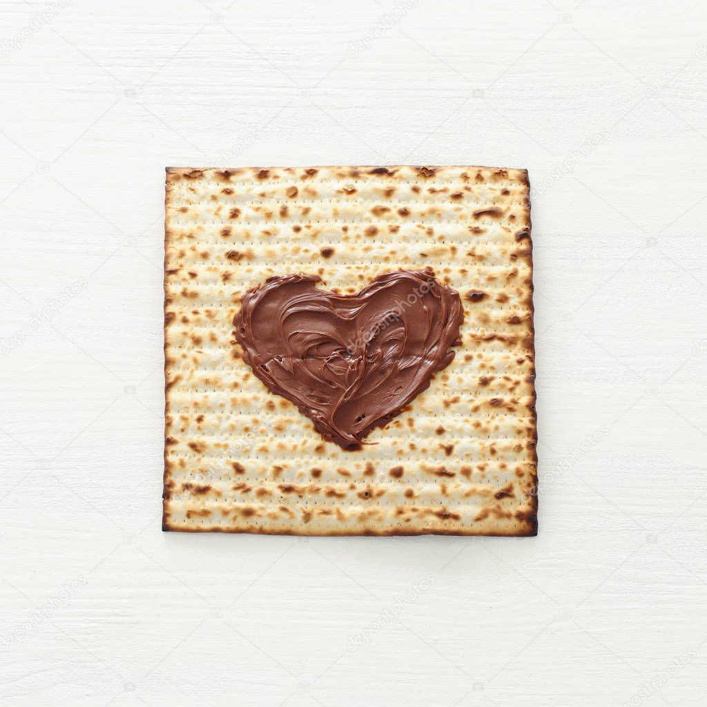 Pesah celebration concept (jewish Passover holiday) with chocolate heart over matzah. Top view flat lay