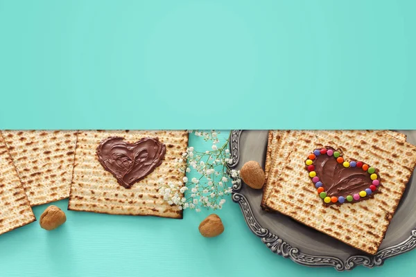Concetto di celebrazione Pesah (festa ebraica Pasqua) con cuore di cioccolato e caramelle colorate su matzah. Vista dall'alto piatto lay — Foto Stock