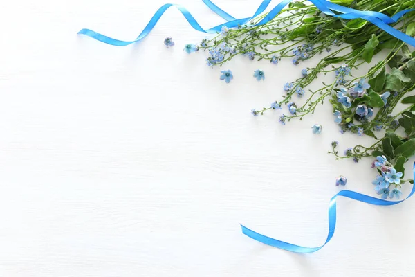 Frühlingsstrauß aus blauen und zarten blauen Blumen vor weißem Holzhintergrund. Draufsicht, flache Lage — Stockfoto