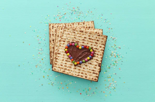 Concepto de celebración de Pesah (fiesta judía de Pascua) con corazón de chocolate y dulces de colores sobre matzah. Vista superior plano laico — Foto de Stock
