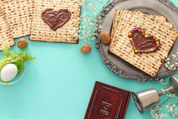 Pesah fest koncept (judisk påsk semester) med choklad hjärta och färgglada godis över matzah. Traditionella bok med text på hebreiska: påsk Haggadah (påsk Sagan) — Stockfoto