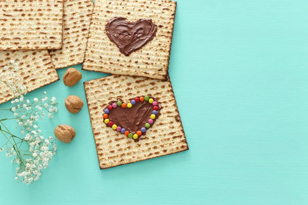 Concetto di celebrazione Pesah (festa ebraica Pasqua) con cuore di cioccolato e caramelle colorate su matzah. Vista dall'alto piatto lay — Foto Stock