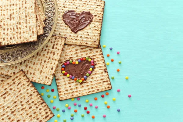 Concetto di celebrazione Pesah (festa ebraica Pasqua) con cuore di cioccolato e caramelle colorate su matzah. Vista dall'alto piatto lay — Foto Stock