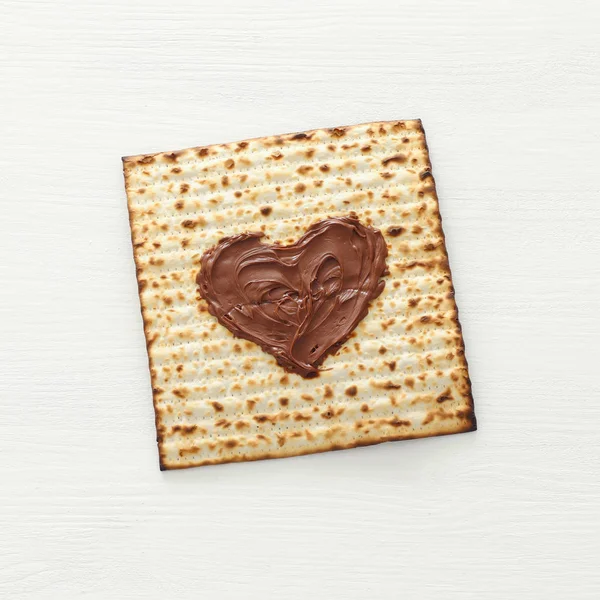 Pesah viering concept (Joodse Pascha vakantie) met chocolade hart over matzah. Bovenaanzicht plat leggen — Stockfoto