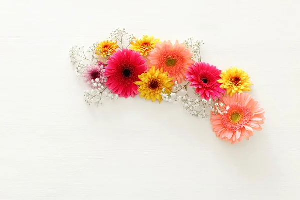 Jarní květy růžové, žluté, oranžové a fialové květy bílé dřevěné pozadí. pohled shora, ploché rozložení — Stock fotografie