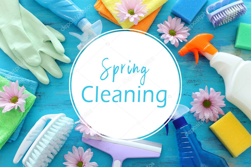 Spring cleaning concept with supplies over blue wooden backgroun