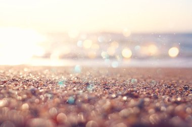 Kumlu kumsal ve parlak bokeh ışıklarıyla okyanus dalgalarının arkaplan görüntüsü