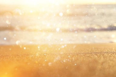 Kumlu kumsal ve parlak bokeh ışıklarıyla okyanus dalgalarının arkaplan görüntüsü