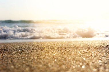 Kumlu kumsal ve parlak bokeh ışıklarıyla okyanus dalgalarının arkaplan görüntüsü