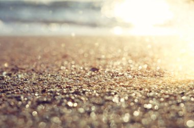 Kumlu kumsal ve parlak bokeh ışıklarıyla okyanus dalgalarının arkaplan görüntüsü