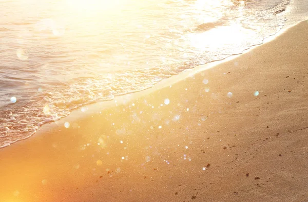 Imagen de fondo de la playa de arena y las olas del océano con luces bokeh brillantes — Foto de Stock