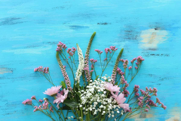 Bouquet primaverile di fiori rosa e bianchi su sfondo blu vintage in legno. vista dall'alto, posizione piatta — Foto Stock