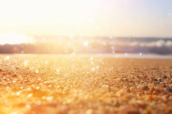 Imagen de fondo de la playa de arena y las olas del océano con luces bokeh brillantes — Foto de Stock