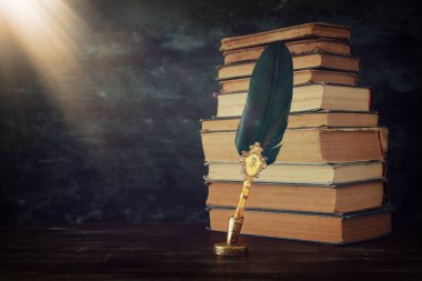Siyah duvar arka plan önünde ahşap masa üzerinde InkWell ve eski kitaplar ile eski tüy Quill mürekkep kalem. Vintage eski tarzı ve filtrelenmiş. Tarih, fantezi, eğitim ve edebiyat üzerine kavramsal fotoğraf t