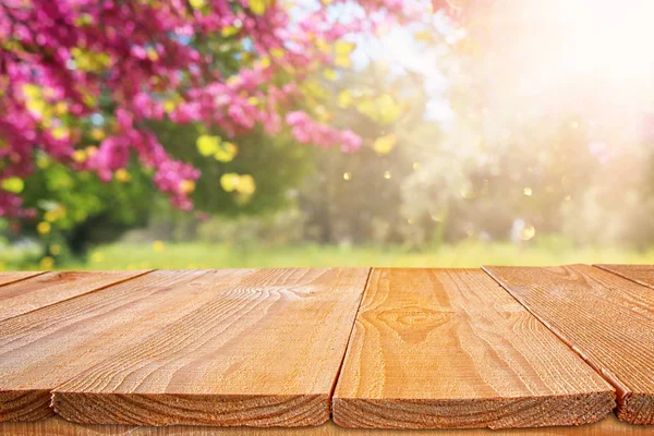 Table en bois devant le paysage des arbres à fleurs printanières. Affichage et présentation des produits — Photo