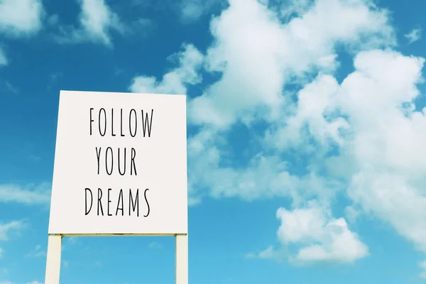 Skylt mot blå himmel med moln med texten-Följ dina drömmar — Stockfoto