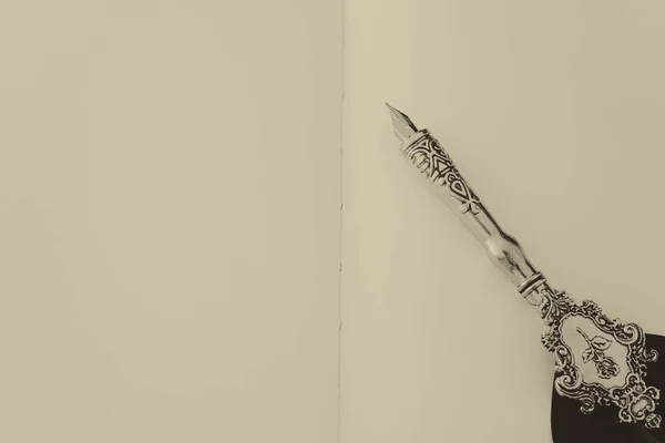 古い羽のペンと空の紙。バックドロップの背景。上から見る。白黒 — ストック写真