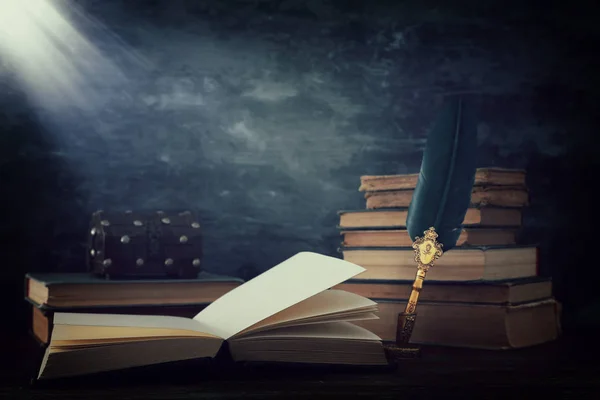 Παλιά πένα φτερό μελάνι στυλό με μελανοδοχείο και παλιά βιβλία πάνω από το ξύλινο γραφείο μπροστά από μαύρο φόντο τοίχο. Εννοιολογική φωτογραφία με θέμα την ιστορία, τη φαντασία, την εκπαίδευση και τη λογοτεχνία — Φωτογραφία Αρχείου