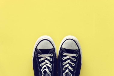 Sarı arka plan üzerinde eski siyah beyaz spor ayakkabıları üst görünümü