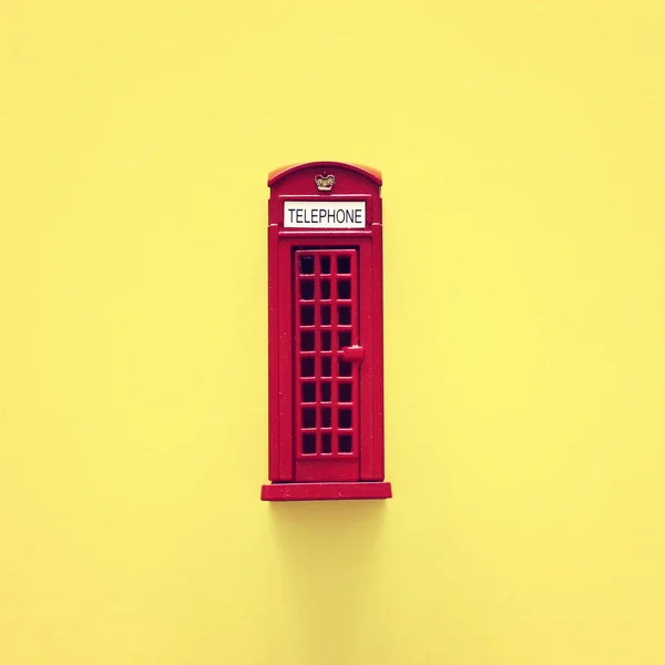 Londyńska tradycyjna czerwona kabina telefoniczna na żółtym tle. — Zdjęcie stockowe