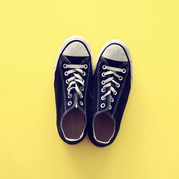 Tampilan atas sepatu hitam dan putih tua di atas latar belakang kuning — Stok Foto