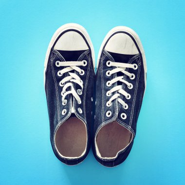 Mavi arka plan üzerinde eski kullanılmış siyah beyaz spor ayakkabıları üst görünümü