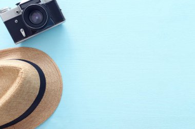 Mavi arka plan üzerinde fedora şapka ve fotoğraf kamerası ile seyahat konseptiüst kesim fotoğrafı