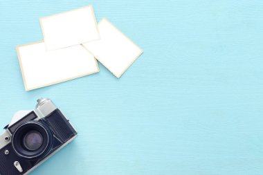 Ahşap masa üzerinde fotoğraf makinesi nin yanındaki boş fotoğrafların üst görünümü. seyahat konsepti. alay etmeye hazır