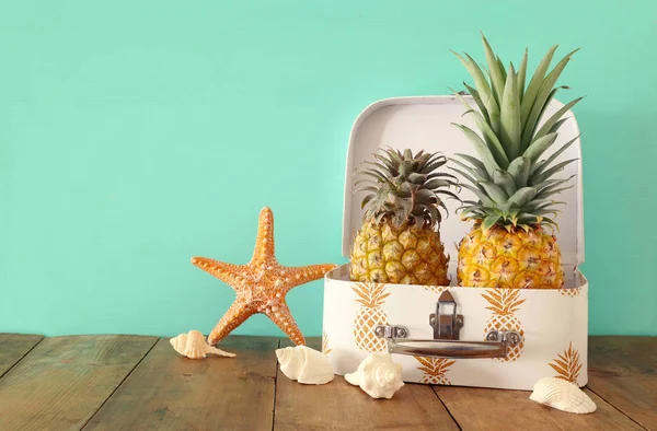 Pareja madura de piña en maleta sobre mesa de madera o cubierta. Concepto de vacaciones de verano tropical — Foto de Stock