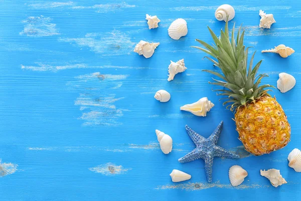 Ripe pineapple over blue wooden background. Beach and tropical theme. Top view
