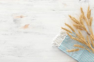 beyaz ahşap arka plan üzerinde buğday bitkileri ve kırsal mutfak havlusu üst görünümü. Yahudi bayramının sembolleri - Shavuot