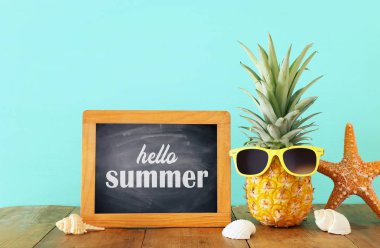 Ahşap masa veya güverte rahatlatıcı üzerinde şık güneş gözlüğü olgun ananas. Tropikal yaz tatili konsepti