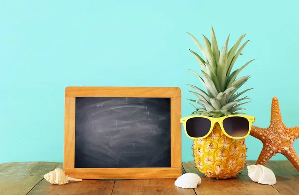 Piña madura en elegantes gafas de sol sobre mesa de madera o cubierta relajante. Concepto de vacaciones de verano tropical — Foto de Stock