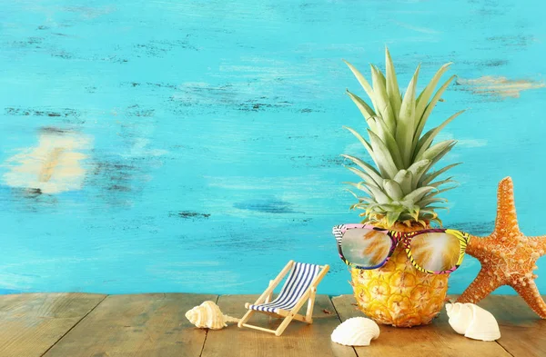 Piña madura en elegantes gafas de sol sobre mesa de madera o cubierta relajante. Concepto de vacaciones de verano tropical — Foto de Stock