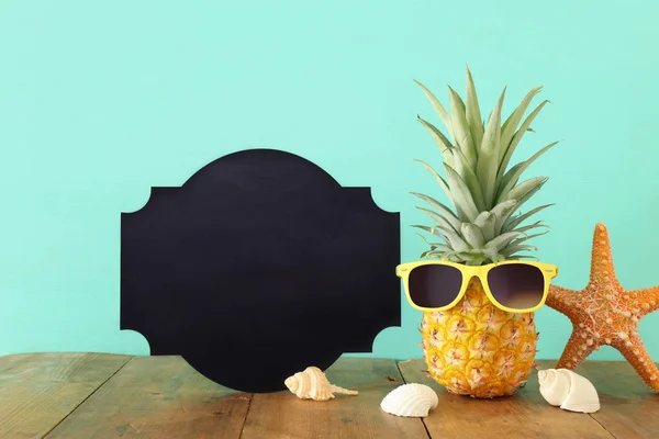 Piña madura en elegantes gafas de sol sobre mesa de madera o cubierta relajante. Concepto de vacaciones de verano tropical —  Fotos de Stock