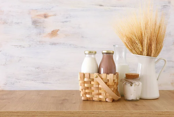 Foto av mjölk och choklad bredvid vete över träbord och vit bakgrund. Symboler för judisk semester-Shavuot — Stockfoto