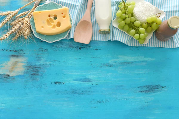 Foto vista dall'alto di prodotti lattiero-caseari su sfondo di legno blu. Simboli di vacanza ebrea - Shavuot — Foto Stock