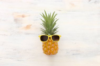 Ahşap beyaz arka plan üzerinde şık güneş gözlüğü olgun ananas. Tropikal yaz tatili konsepti. üst vew