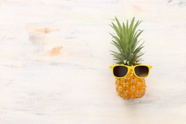 Ahşap beyaz arka plan üzerinde şık güneş gözlüğü olgun ananas. Tropikal yaz tatili konsepti. üst vew