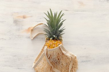 beyaz ahşap arka plan üzerinde ananas ile alışveriş çantası. Plaj ve tropikal tema. Üstte görüntü