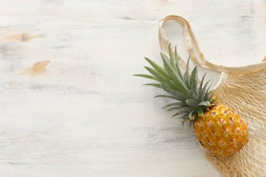 beyaz ahşap arka plan üzerinde ananas ile alışveriş çantası. Plaj ve tropikal tema. Üstte görüntü