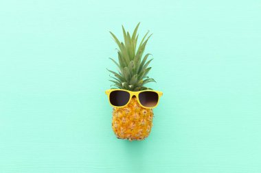 Ahşap mavi arka plan üzerinde şık güneş gözlüğü olgun ananas. Tropikal yaz tatili konsepti. üst vew