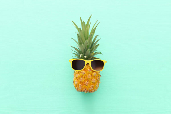 Ripe pineapple in stylish sunglasses over wooden blue background. Tropical summer vacation concept. top vew