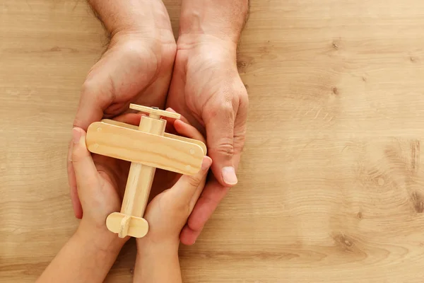 Photo of father and little child holding together wooden toy plane. Happy father's day and holiday concept. top view, above — Stock Photo, Image