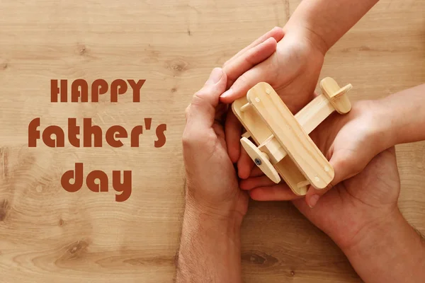 Photo of father and little child holding together wooden toy plane. Happy father's day and holiday concept. top view, above — Stock Photo, Image