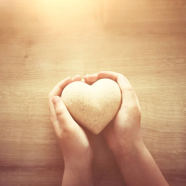 Little child holding a wooden heart. father's and mother's day, love, hope and religion concept. — Stock Photo, Image