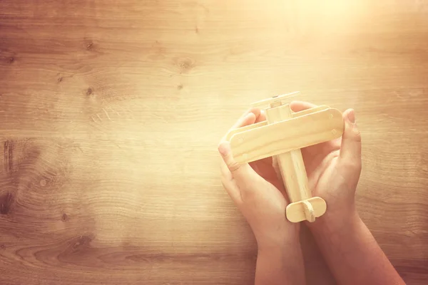 Foto del niño pequeño sosteniendo avión de juguete de madera. Feliz día del padre y el concepto de vacaciones. vista superior, arriba — Foto de Stock