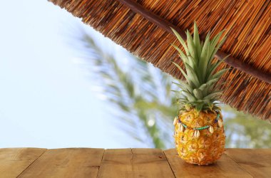 Plaj ve tropikal arka plan önünde ahşap masa üzerinde Olgun ananas