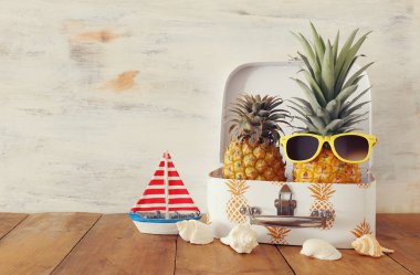Ahşap masa veya güverte üzerinde bavul içinde olgun çift ananas. Tropikal yaz tatili konsepti