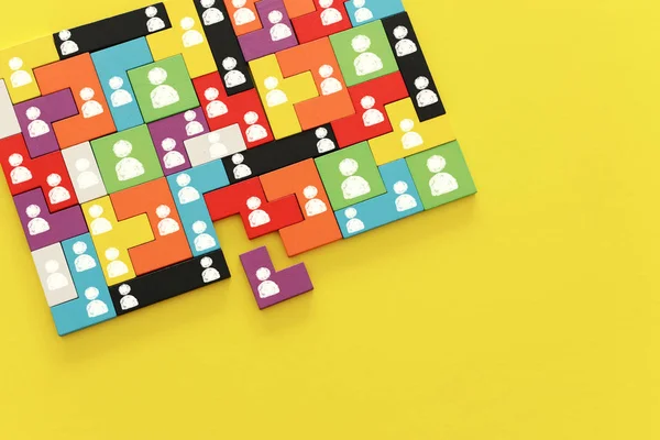 Bild von Tangram-Puzzleblöcken mit Menschen-Symbolen über hölzernen Tab — Stockfoto